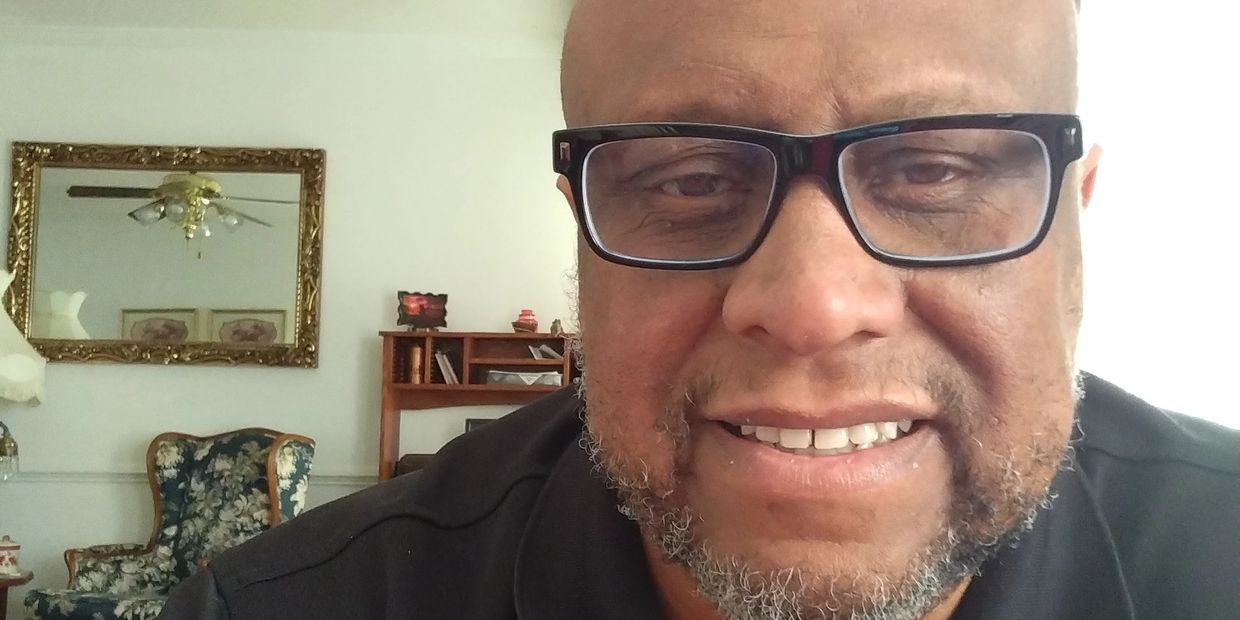 Close-up of a smiling man with glasses indoors.