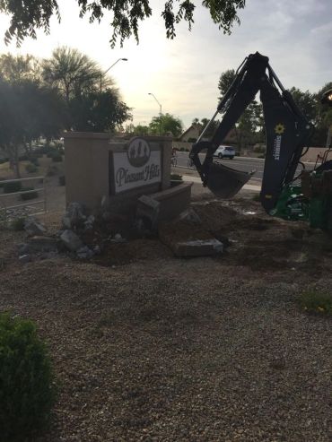 Excavator digging near a Passion Place sign in a residential area during sunset.