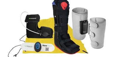 A set of electronic foot and leg braces with control units and a yellow mat.