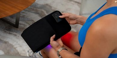 Person holding a black electronic heating pad, highlighting knee pain relief.