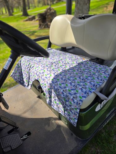 Golf cart seat covered with a golf-themed shirt.