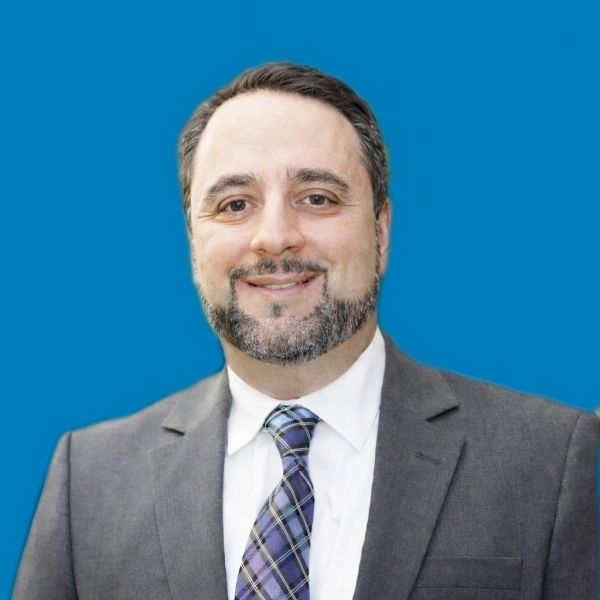 Smiling man in a suit with a blue background.