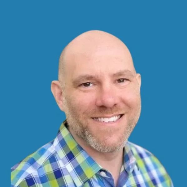 Smiling bald man in a blue and green plaid shirt.