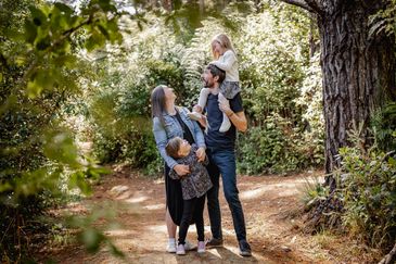 Family enjoying a walk in a lush forest, sharing joyful moments together.
