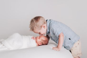 Big brother kissing newborn baby in Studio portrait session with Sunshine Studios NZ Wellington