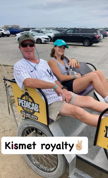 Two people relaxing on a pedicab near a parking lot, smiling and enjoying their time.