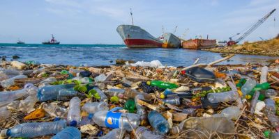 Polluted shoreline littered with plastic waste and abandoned ships.