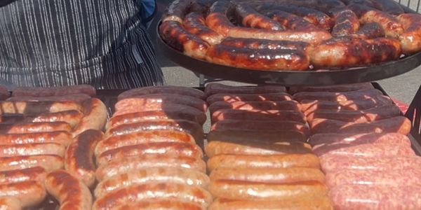 Assorted sausages being grilled outdoors at a food stall.