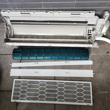 Disassembled air conditioner components laid out neatly on the ground.