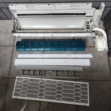 Disassembled air conditioner parts laid out on the floor.