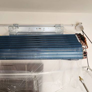 Exposed indoor air conditioner evaporator coil with copper tubing.