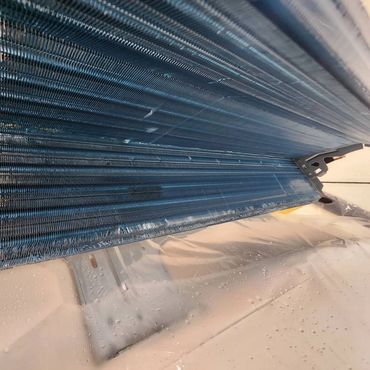 Close-up of an air conditioner evaporator coil with frost buildup.