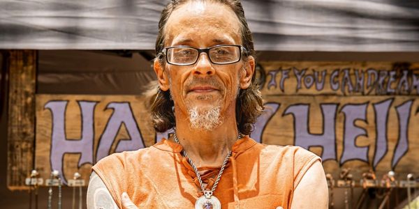 Man with glasses and a pendant necklace.