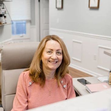 Smiling woman sitting at a desk in a bright office.