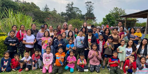 Large diverse group of children and adults posing outdoors in a natural setting.