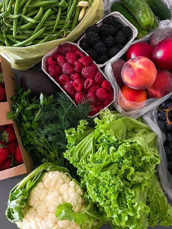 Fresh fruits and vegetables including berries, peaches, lettuce, and cauliflower.