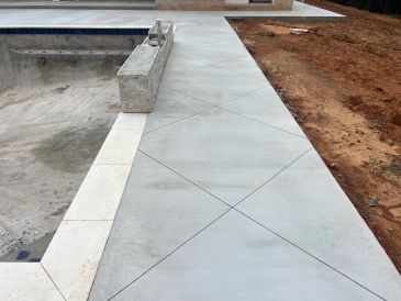 Concrete sidewalk next to an unfinished pool.