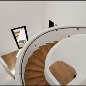 Modern spiral staircase with wooden steps and white railing.