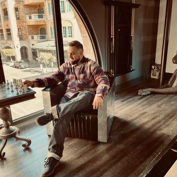 This image shows a professional haircut in a room with a nice view and a chess table.
