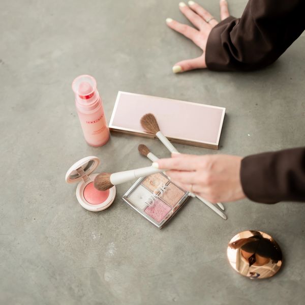 A person applying makeup with brushes on a concrete surface.