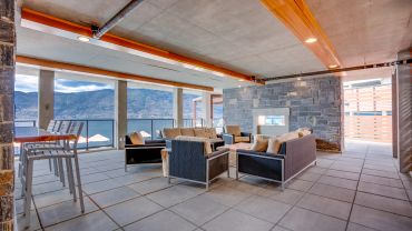 Modern lounge with stone walls and large windows overlooking a lake.