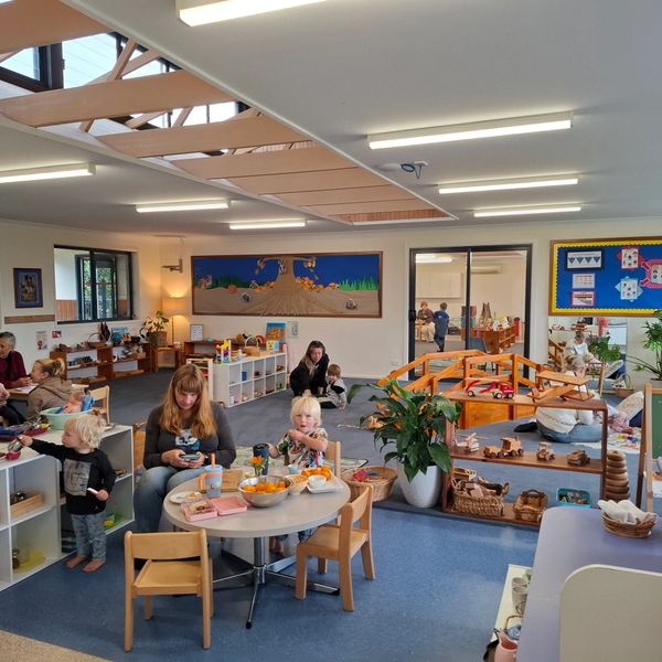 Children and adults engaging in activities in a bright, organized preschool classroom.