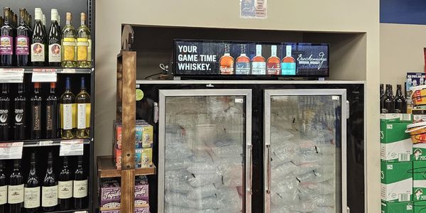 Refrigerator with whiskey bottles and wine shelves in a store.