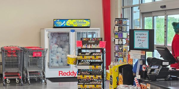 Store checkout area with shopping carts and display racks.