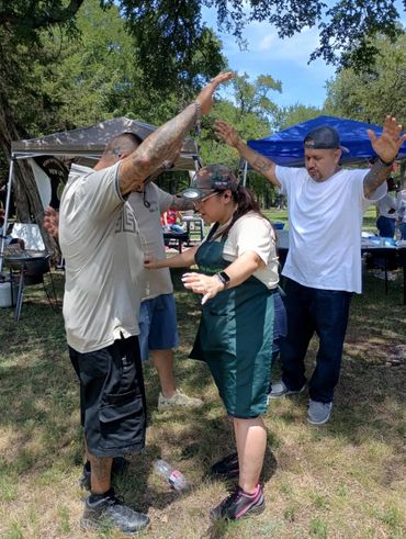 People enjoying an outdoor gathering with raised hands and smiles.