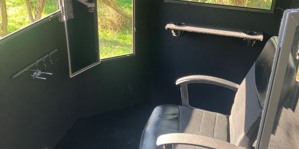 Interior of a shooting range booth with a chair and window openings.