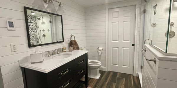 Modern bathroom with dark vanity and white walls.