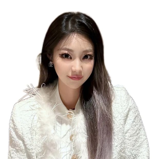 A young woman with long hair wearing a white textured jacket and earrings.