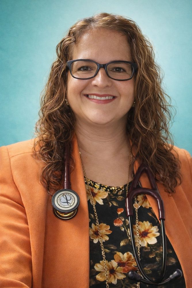 Smiling female doctor with curly hair and glasses.