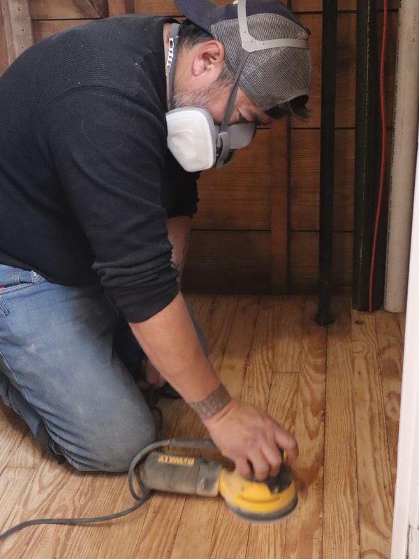 Worker sanding wood floor.