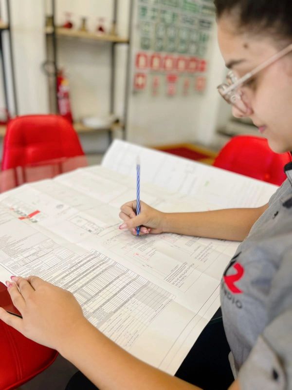 A woman reviewing and marking a large blueprint or technical document.