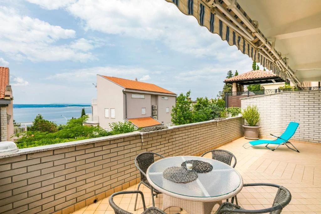 Balcony with table, chairs, and sea view.