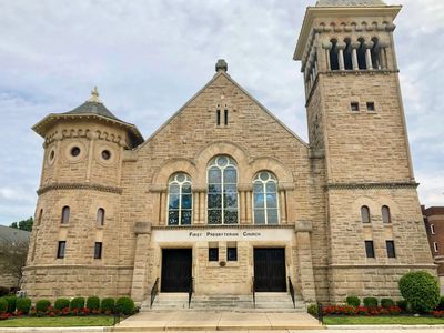 Stone facade of First Presbyterian Church with arched windows and towers.