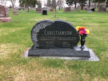 Gravestone in a cemetery with flowers in a vase.