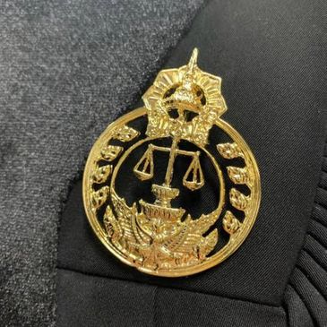 Gold emblem with scales of justice on black fabric.