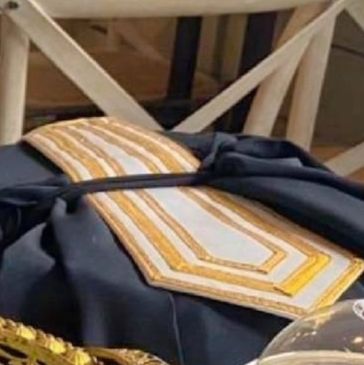 Black and gold ceremonial robe draped over a chair with intricate designs.