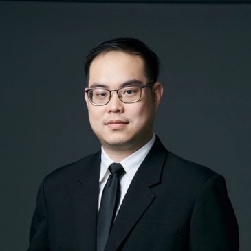 Professional man in glasses and black suit against a dark background.