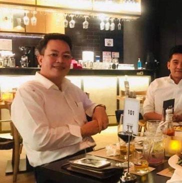 Two men dining at a restaurant table with food and drinks.