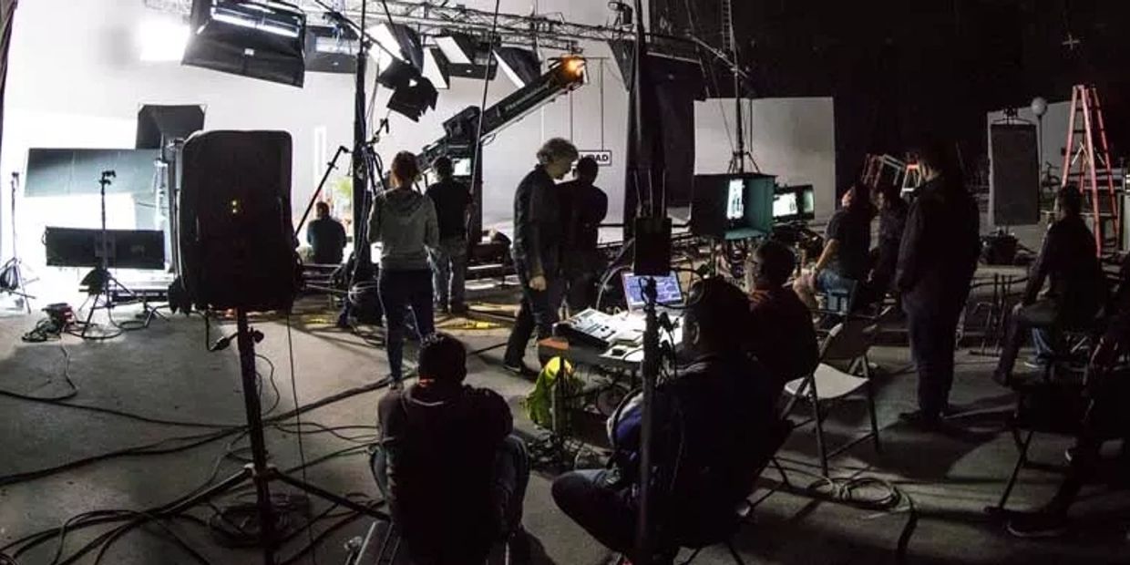 A busy film set with crew members and lighting equipment in action.