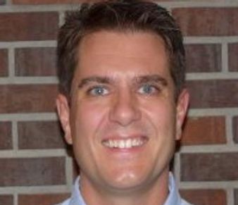 Smiling man with brick wall background.