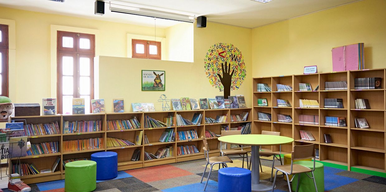 One corner of the library features bookcases along the wall and a round table with chairs and stools