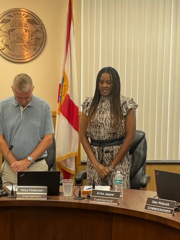 Two commissioners standing in a meeting room.