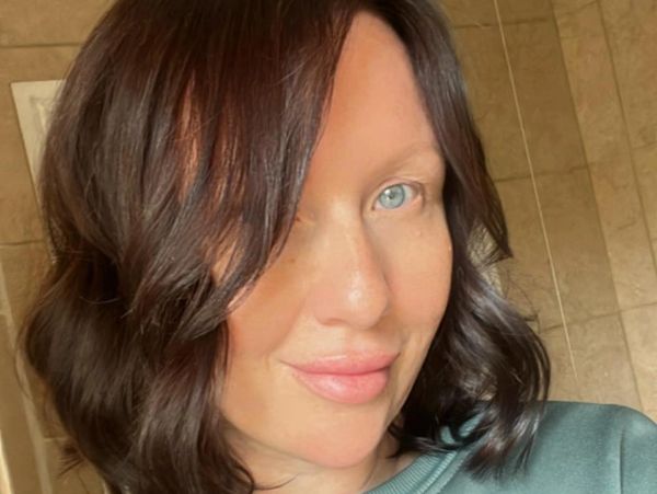 Close-up portrait of a woman with wavy brown hair and blue eyes.