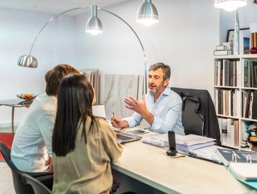 A consultant talking to a couple across a desk in an office.