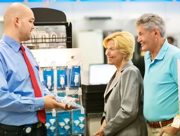 Two business people talking to a smiling client in a store.