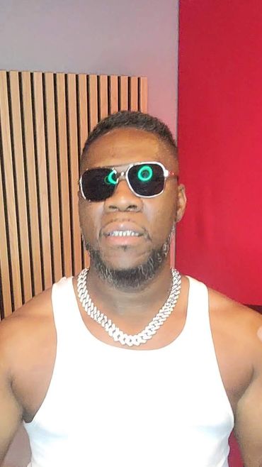Man wearing sunglasses, white tank top, and chain necklace.